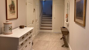 A hallway with a staircase, a white dresser with drawers, a framed picture on the wall, and a vase with flowers. - Holiday Home 'Feel at Home in Different Spaces' with Wi-Fi (Heide)