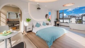 A modern bedroom with a large bed, a desk, and a view of the city. - First Sight Yingshan Resort (Dali)