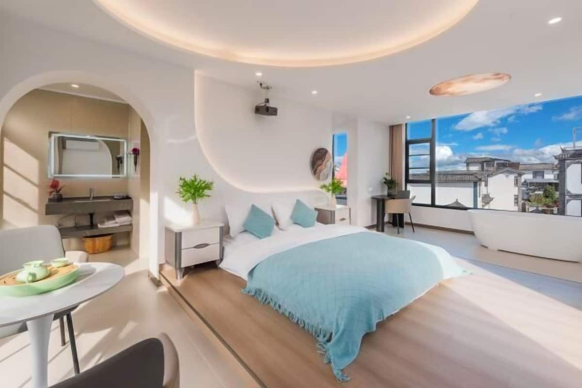 Un dormitorio moderno con una cama grande, un escritorio y vistas a la ciudad.
