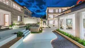A modern residential building with a courtyard, outdoor seating, and a well-lit entrance. - First Sight Yingshan Resort (Dali)