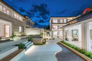 A modern residential building with a courtyard, outdoor seating, and a well-lit entrance. - First Sight Yingshan Resort (Dali)