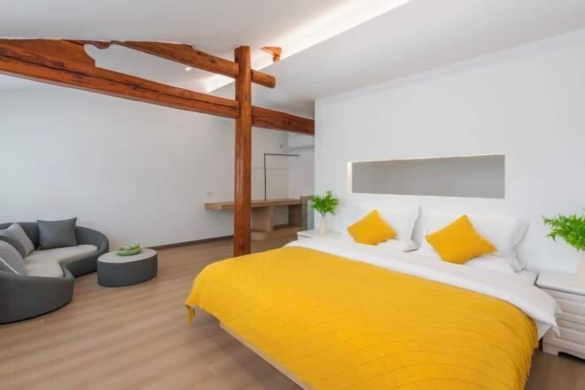 Un dormitorio moderno con una cama grande, un sofá y una viga de techo de madera.