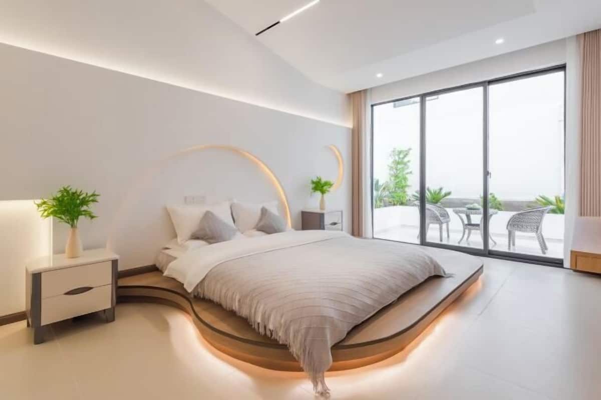 Un dormitorio moderno con una cama curvada, mesitas de noche y un gran ventanal que ofrece vistas al exterior.