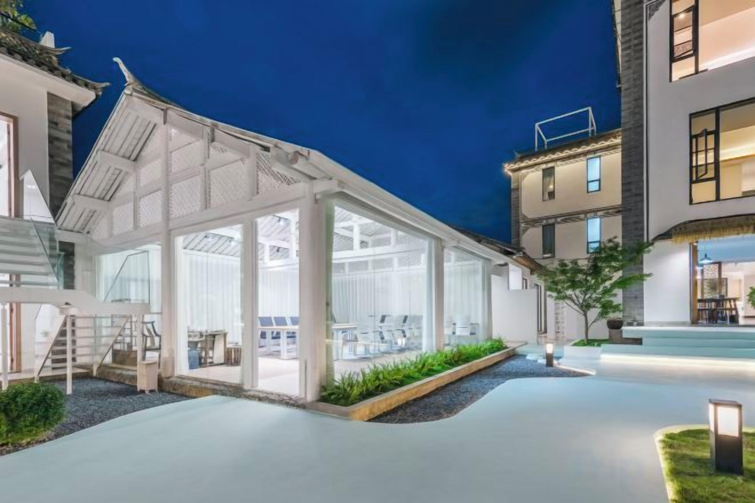 A modern house with a glass conservatory, a covered outdoor area, and a well-lit entrance.