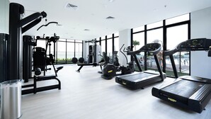 A modern gym with various exercise equipment, large windows, and a clean, spacious layout. - Modern Studio in Azizi Riviera 46  (Dubai)