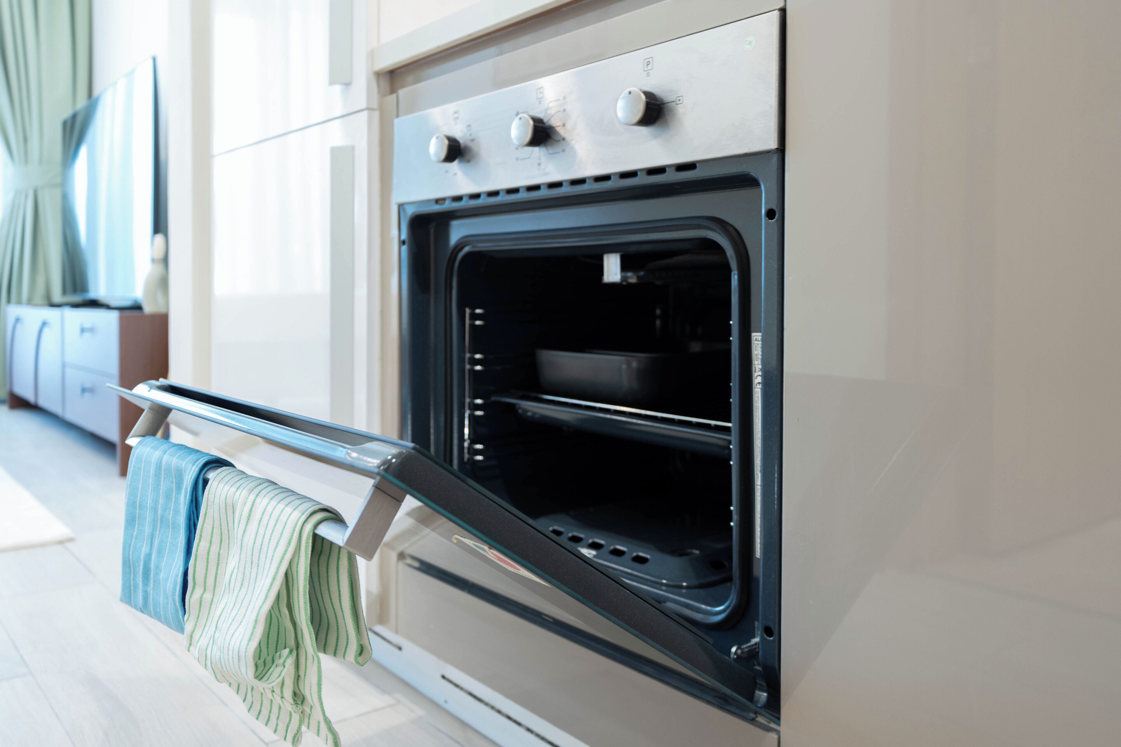 An open oven with a towel hanging on the handle.