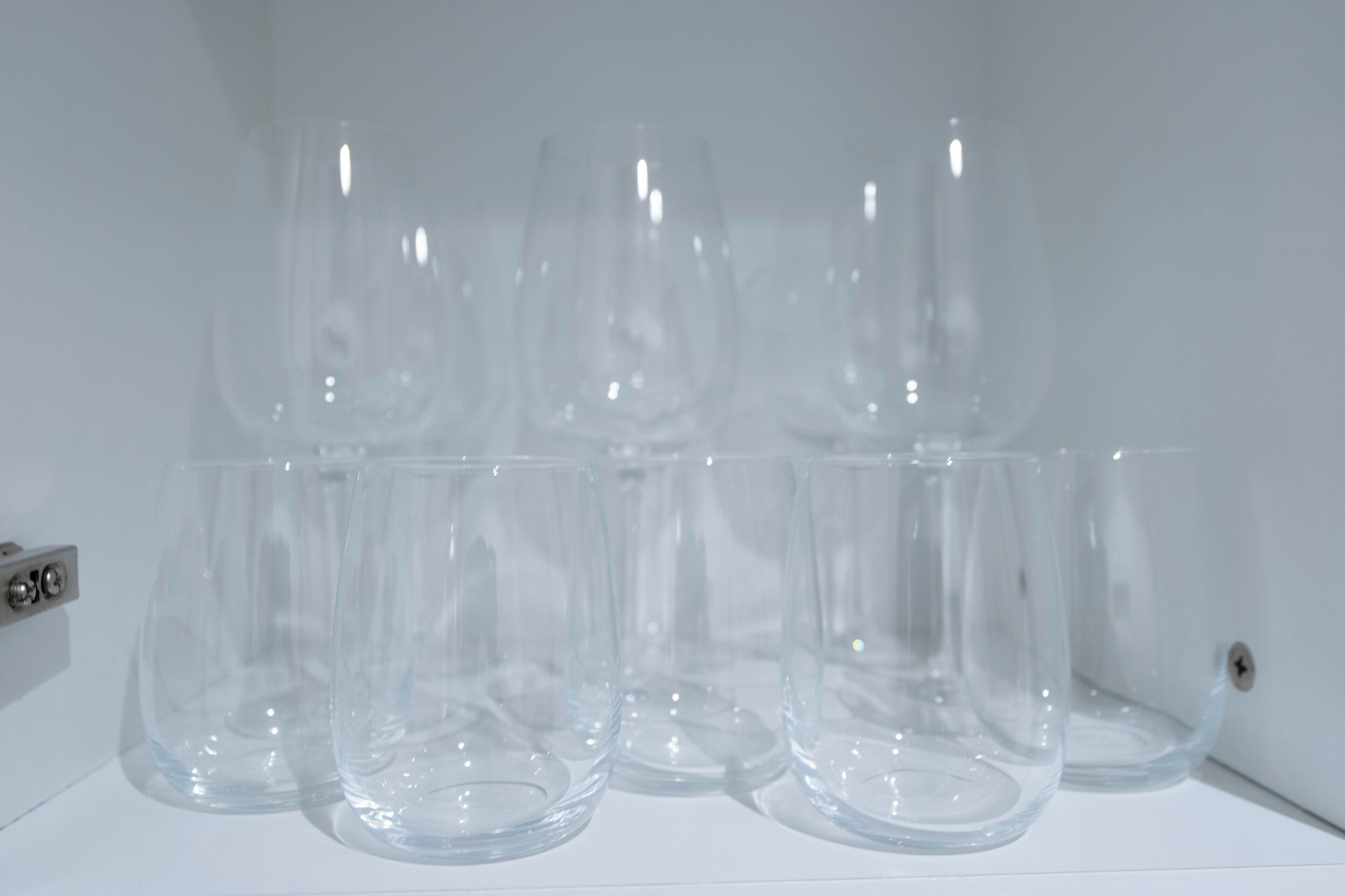 A row of clear glass tumblers on a white surface.