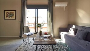 A living room with a sofa, a chair, a coffee table with a plant, and a view through a glass door. - 1-BR flat with terrace -Eixample (Barcelona)