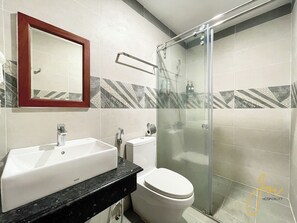 A bathroom with a white sink, a toilet, and a glass-enclosed shower stall. - Joi Boutique Bãi Sau  (Ho Chi Minh City)