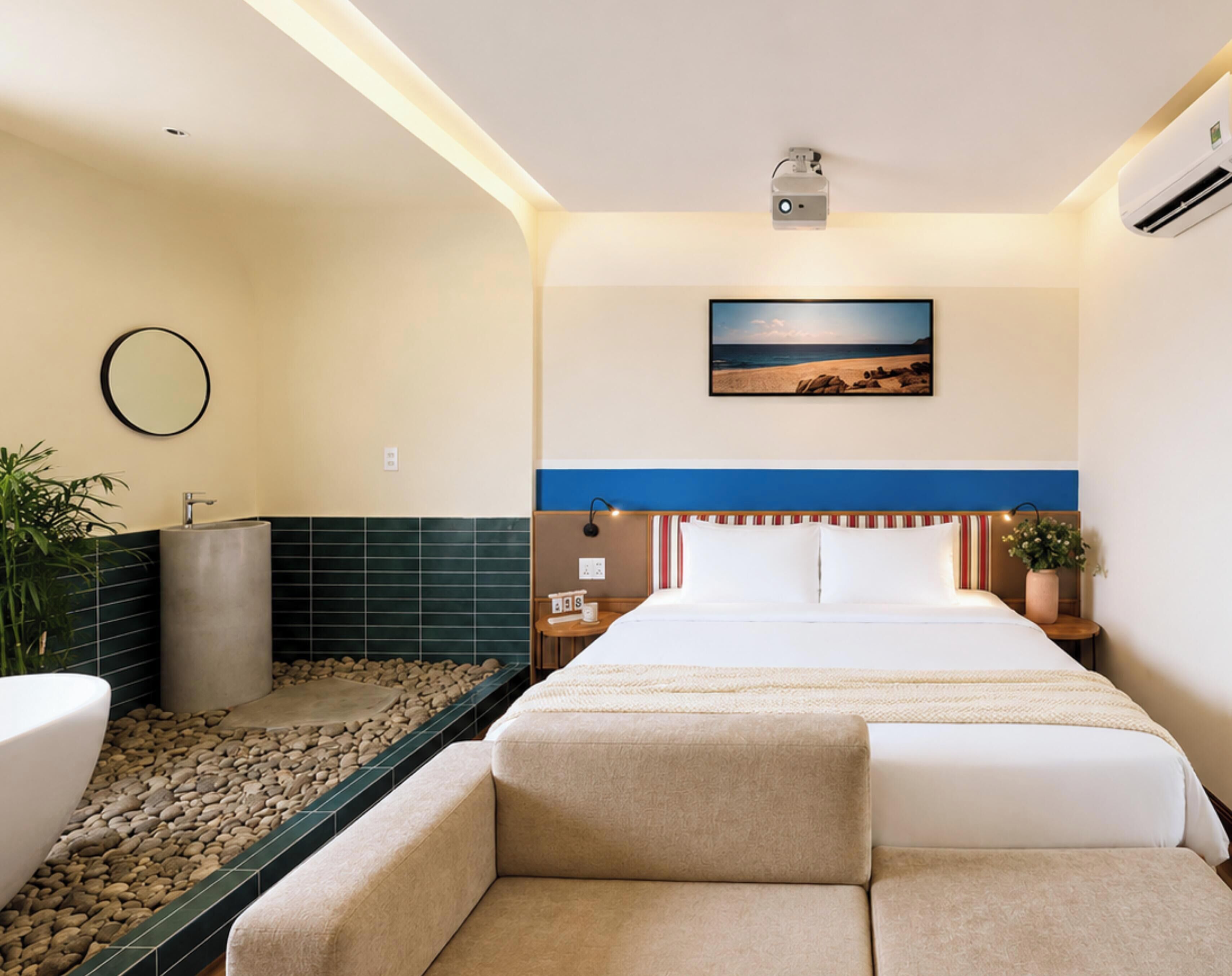 A hotel room with a bed, a bedside table, a nightstand, a mirror, a picture on the wall, and a small potted plant.