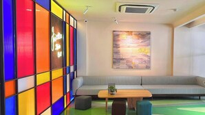 A modern lounge with a colorful wall, a striped sofa, a wooden coffee table, and a minimalist abstract painting. - Joi Boutique Bãi Sau  (Ho Chi Minh City)