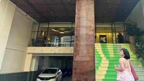 A building with a large central column, a staircase with green steps, and a parked car. - Joi Boutique Bãi Sau  (Ho Chi Minh City)