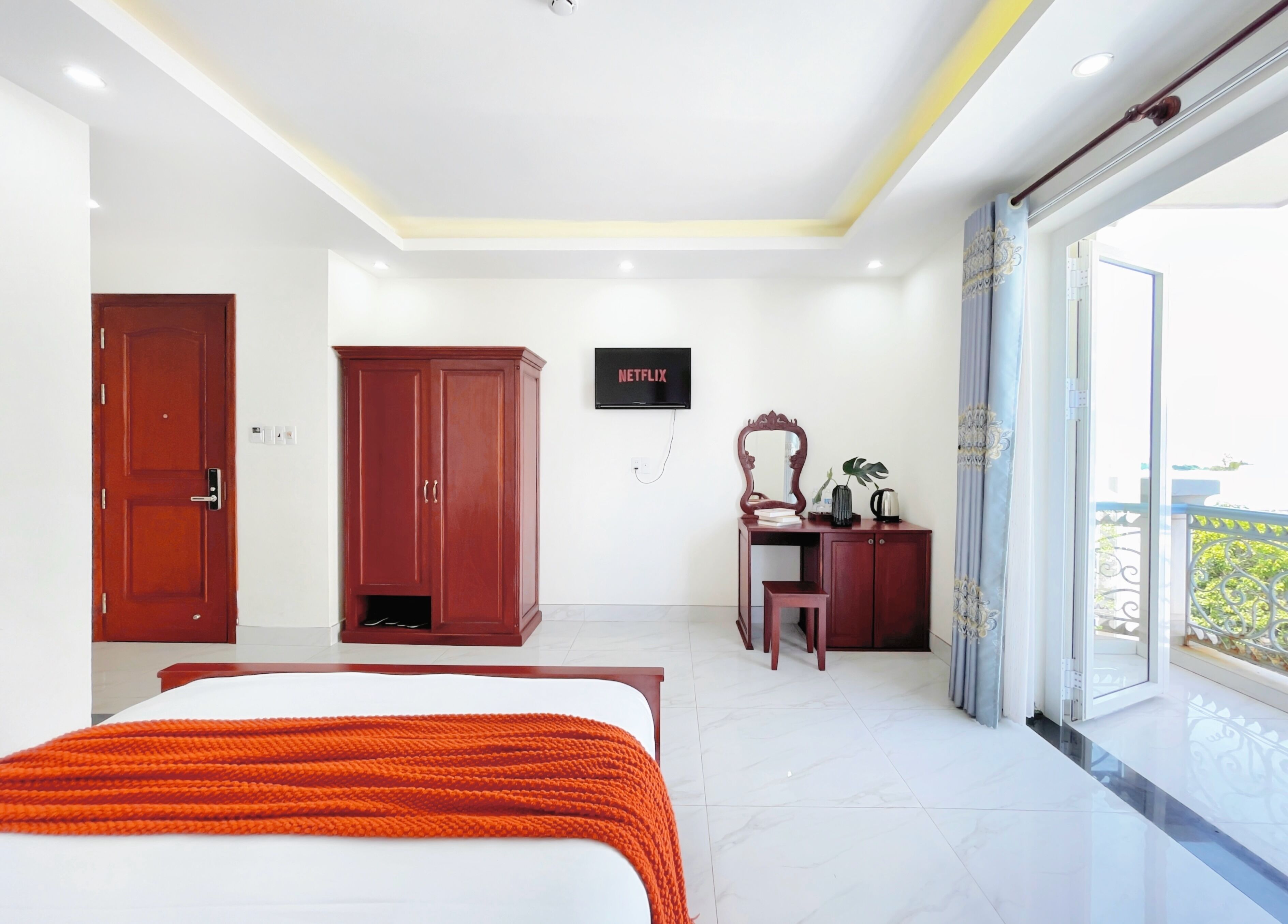 A bedroom with a bed, wardrobe, desk, and a TV.