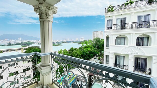 A balcony with ornate metal railings overlooking a cityscape with buildings and greenery. - Joi Boutique Bãi Sau  (Ho Chi Minh City)