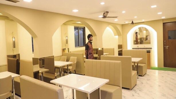 A modern restaurant with high ceilings, recessed lighting, and a central island. - Hotel Devanshri Rooms & Restaurant (Pen)