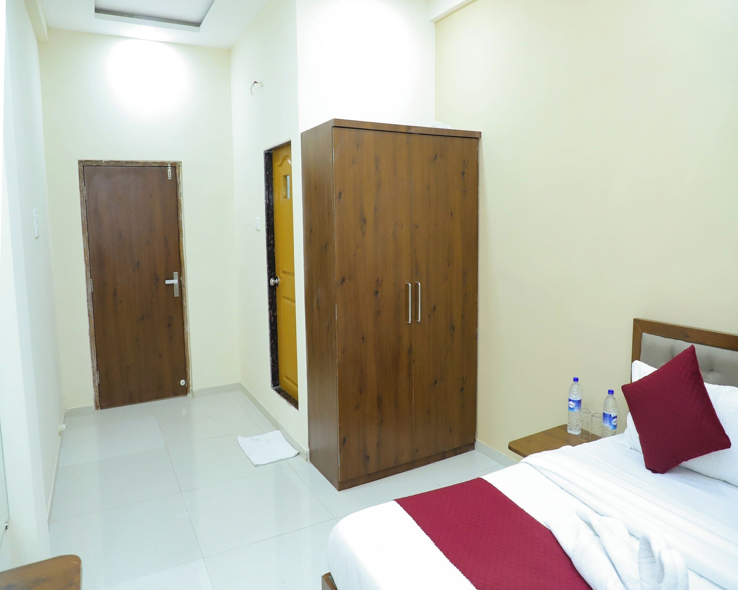 A hotel room with a bed, a wardrobe, a nightstand, and a water bottle.
