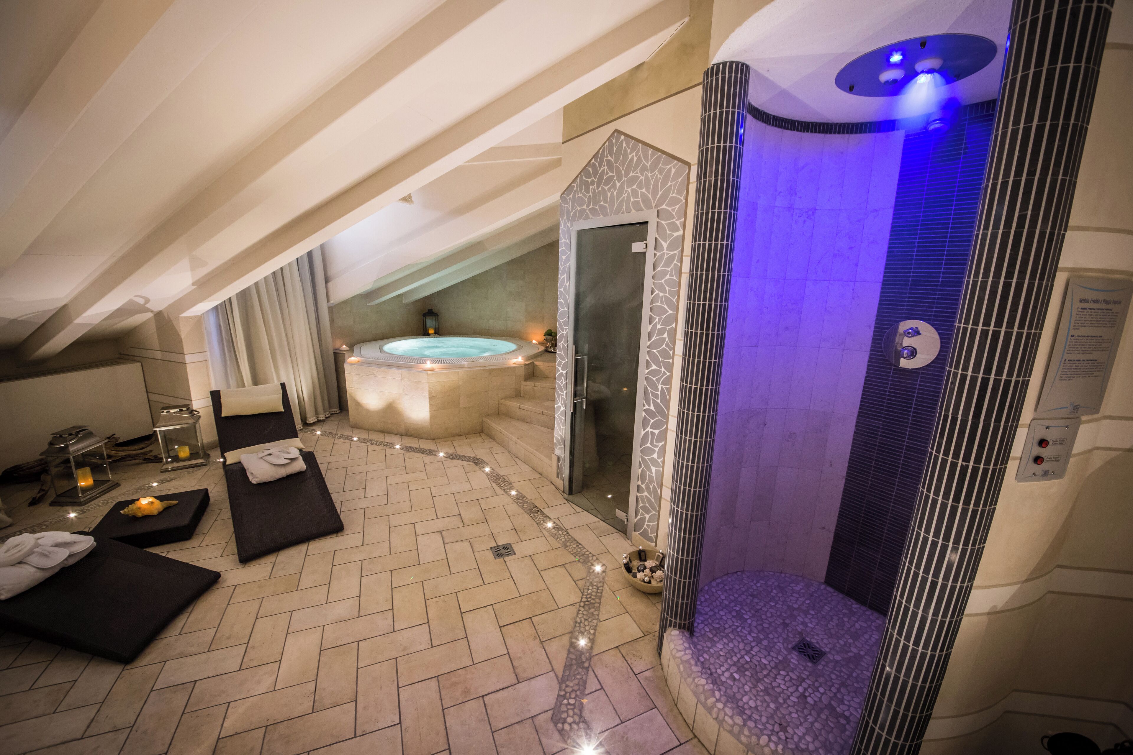 Un área de spa con hidromasaje, camillas de masaje y ducha a pie.
