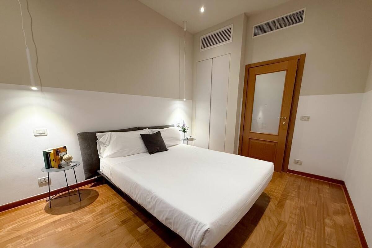 A neatly arranged bedroom with a bed, bedside table, and a wardrobe.