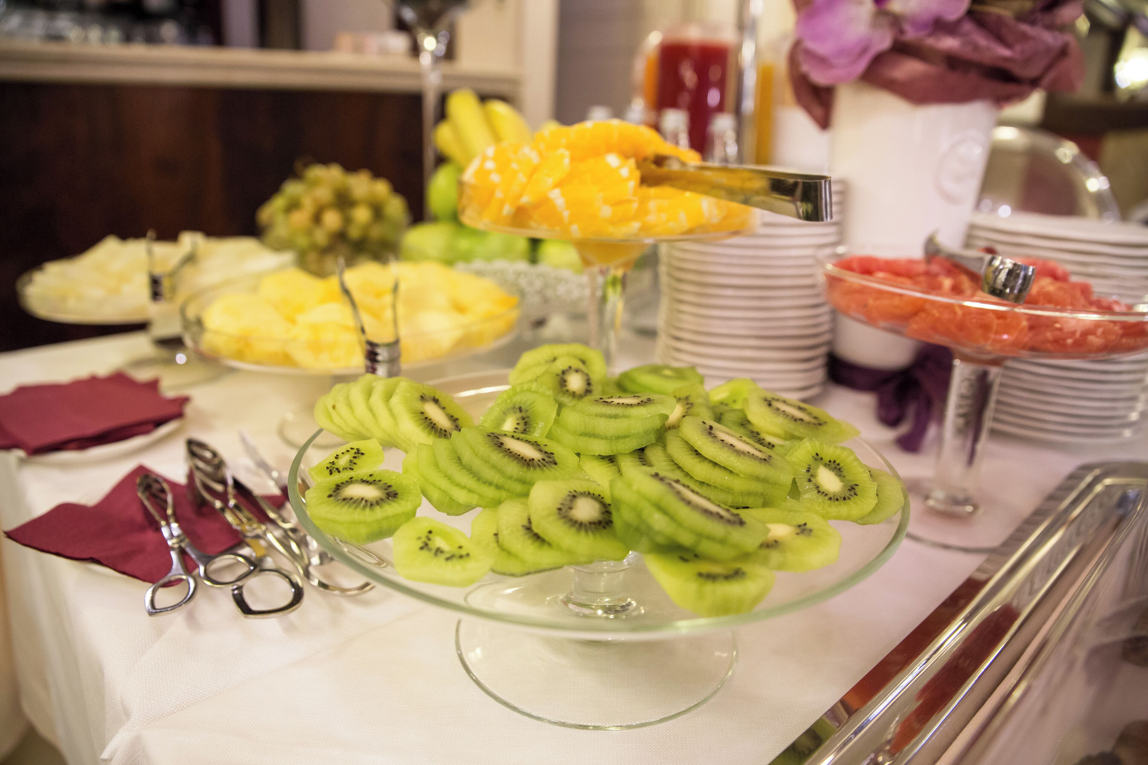 Un bufé con diversas frutas y un recipiente de vidrio para servir.