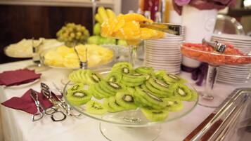 Un bufé con diversas frutas y un recipiente de vidrio para servir.