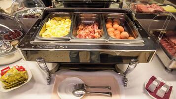 A buffet with various food options including eggs, ham, and oranges.