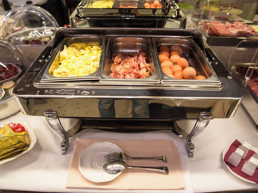 A buffet with various food options including eggs, ham, and oranges.