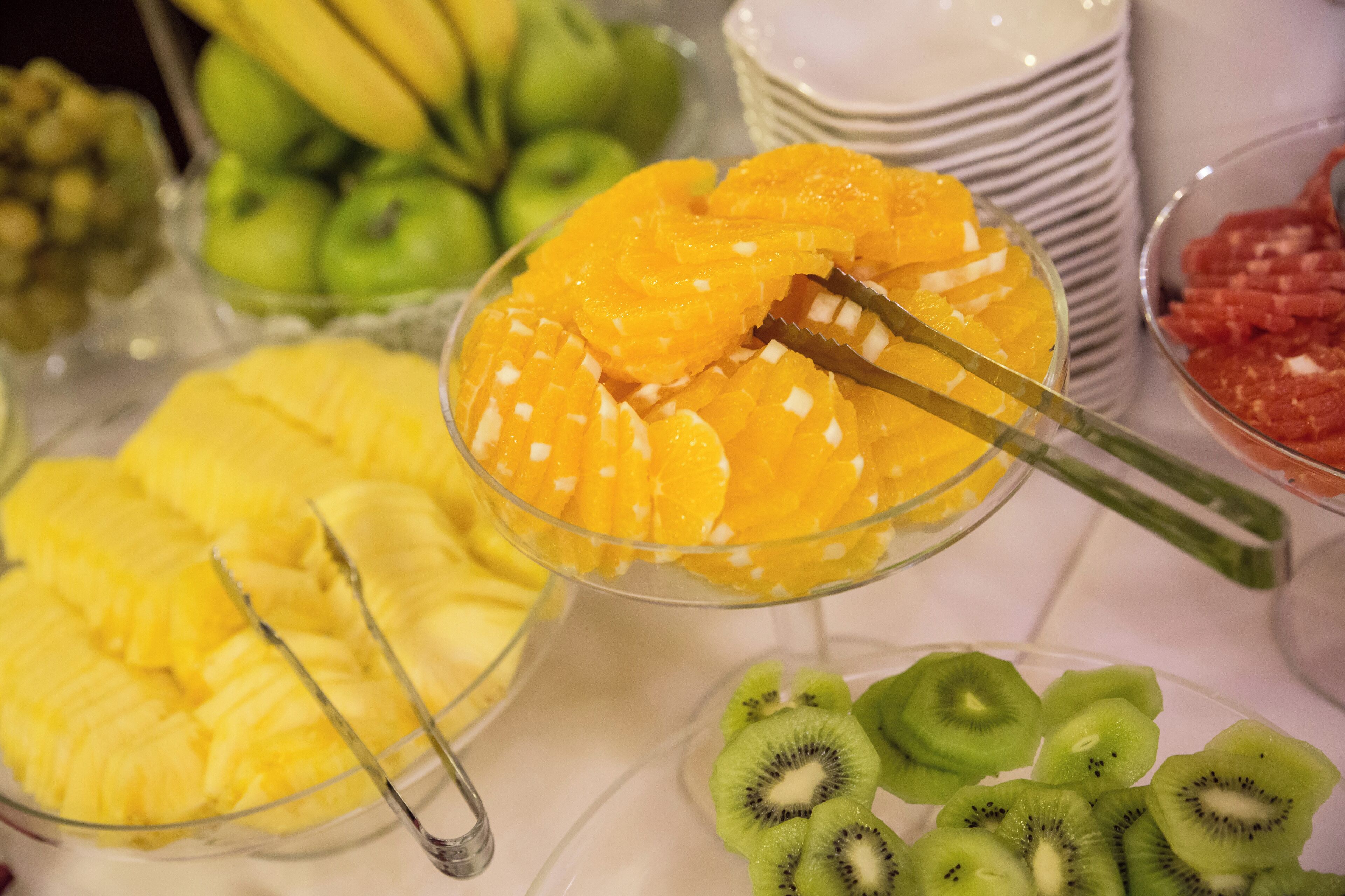 A buffet with various fruits including pineapple, orange, and kiwi slices.