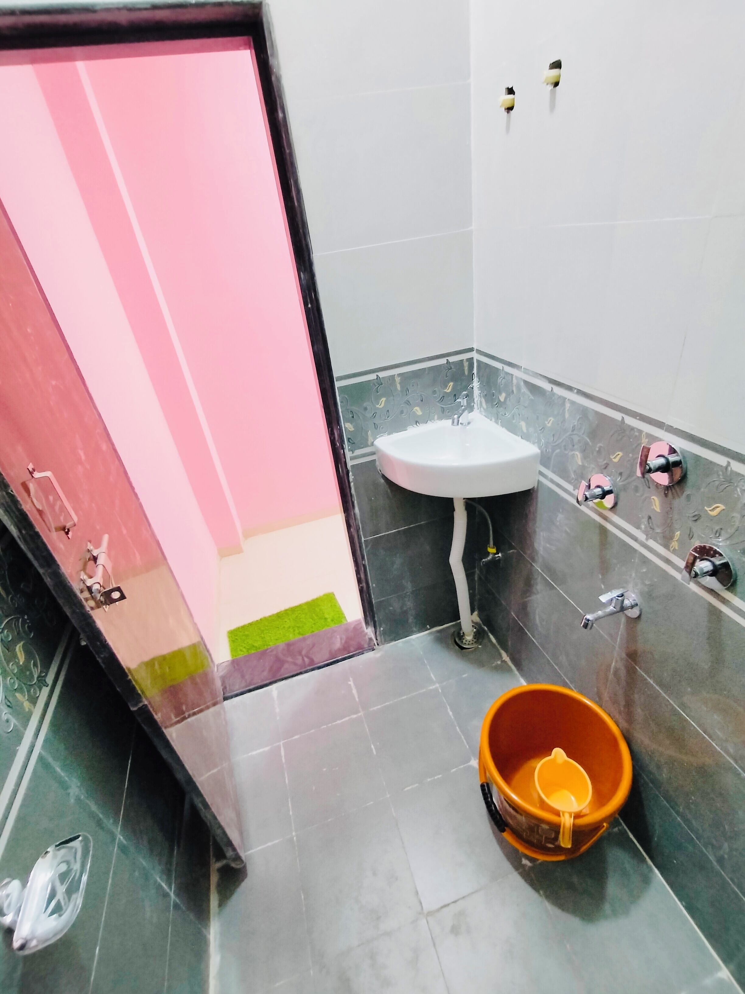 Ein Badezimmer mit Waschbecken, Spiegel und Toilette. Ein Eimer steht auf dem Boden.