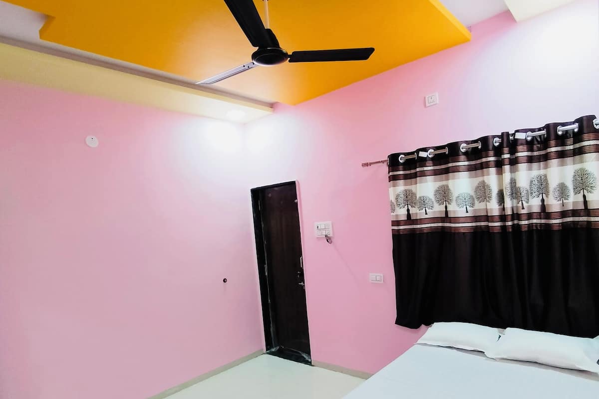 Ein Schlafzimmer mit einem Bett, einem Deckenventilator, einer Tür und einem Vorhang.