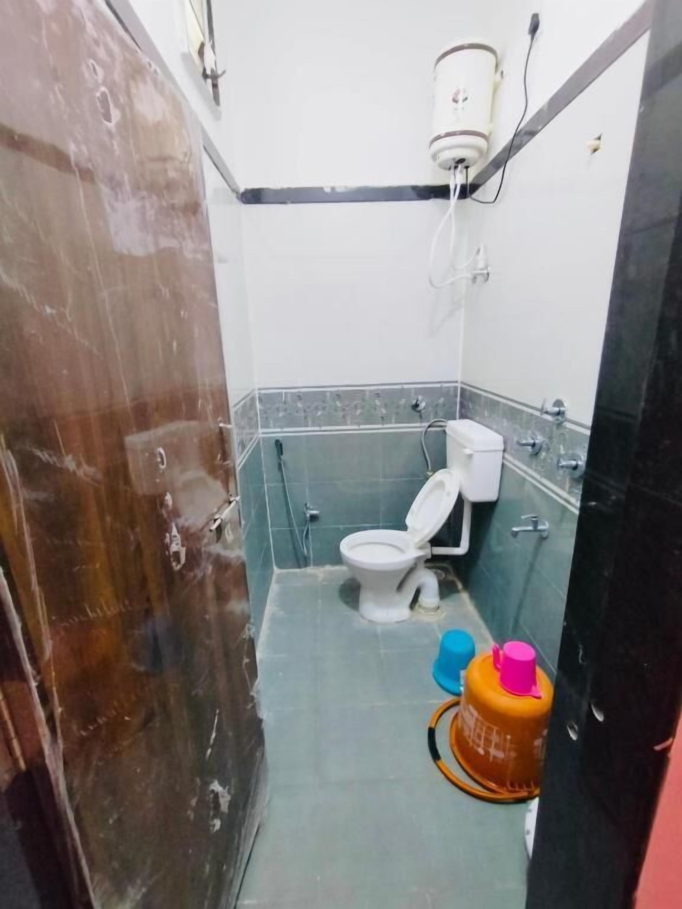 A small bathroom with a toilet, a shower, and a sink. There is a mirror on the wall and a towel hanging on the door.
