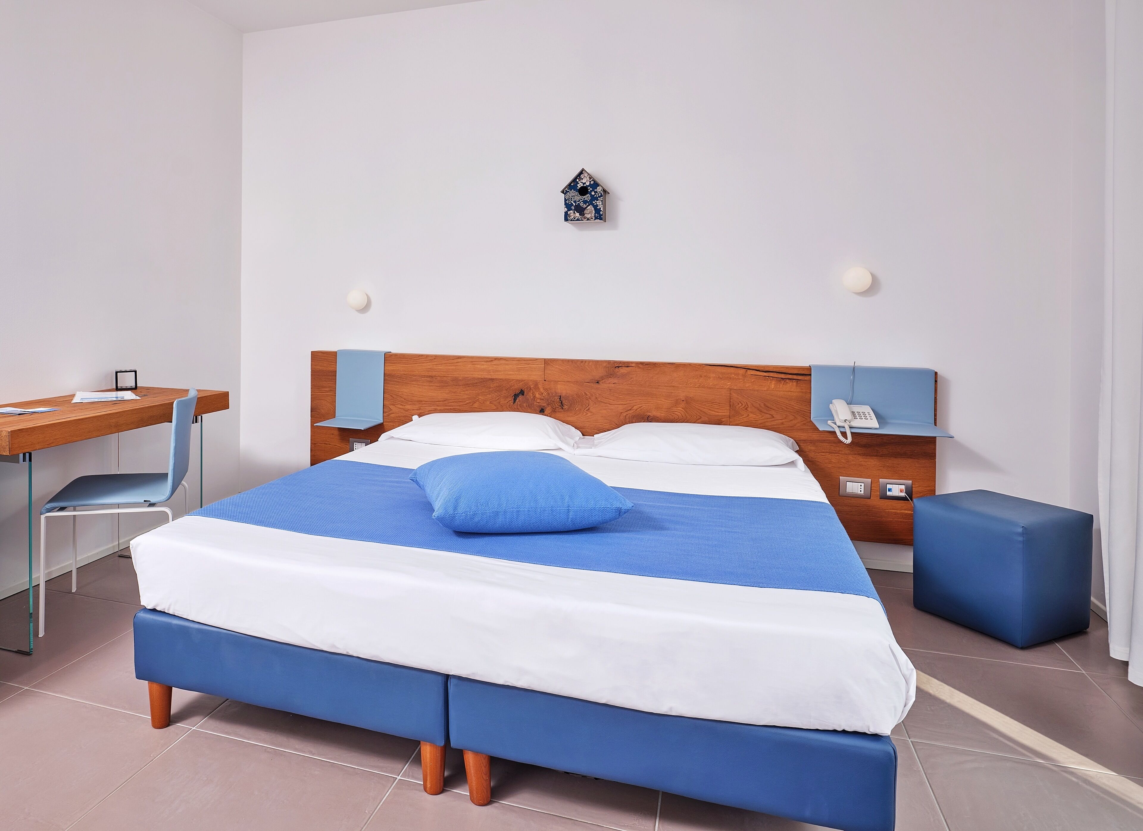 A neatly arranged bedroom with a wooden bed, a desk, and a chair.