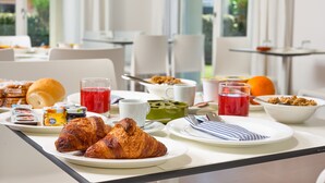 Una mesa de desayuno con cruasanes, jugo y diferentes productos para el desayuno.