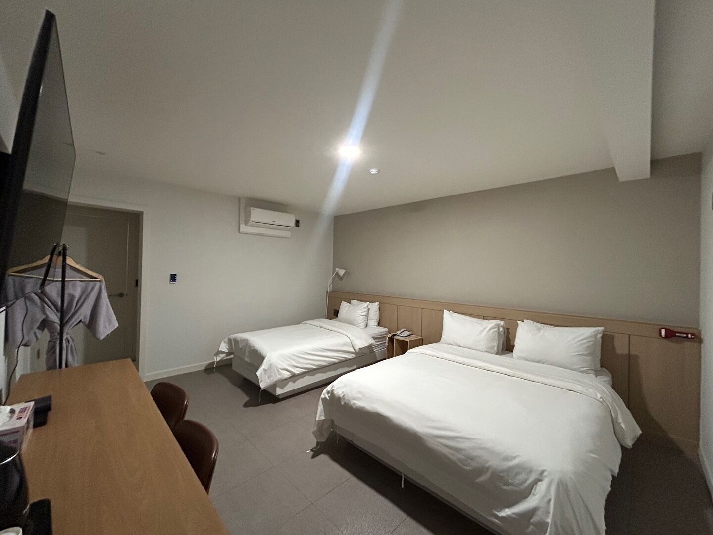 A hotel room with two single beds, a desk, and a chair.