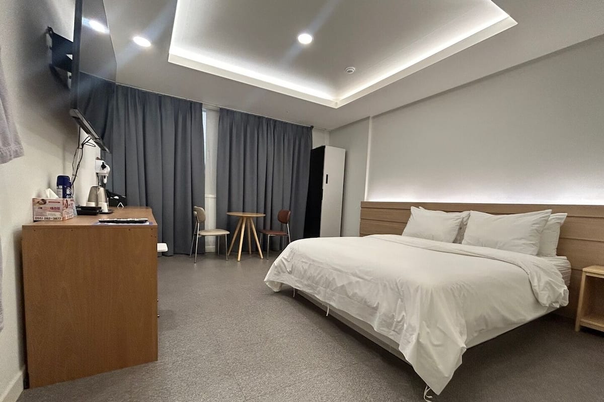 A modern hotel room with a large bed, a desk, and a small table.