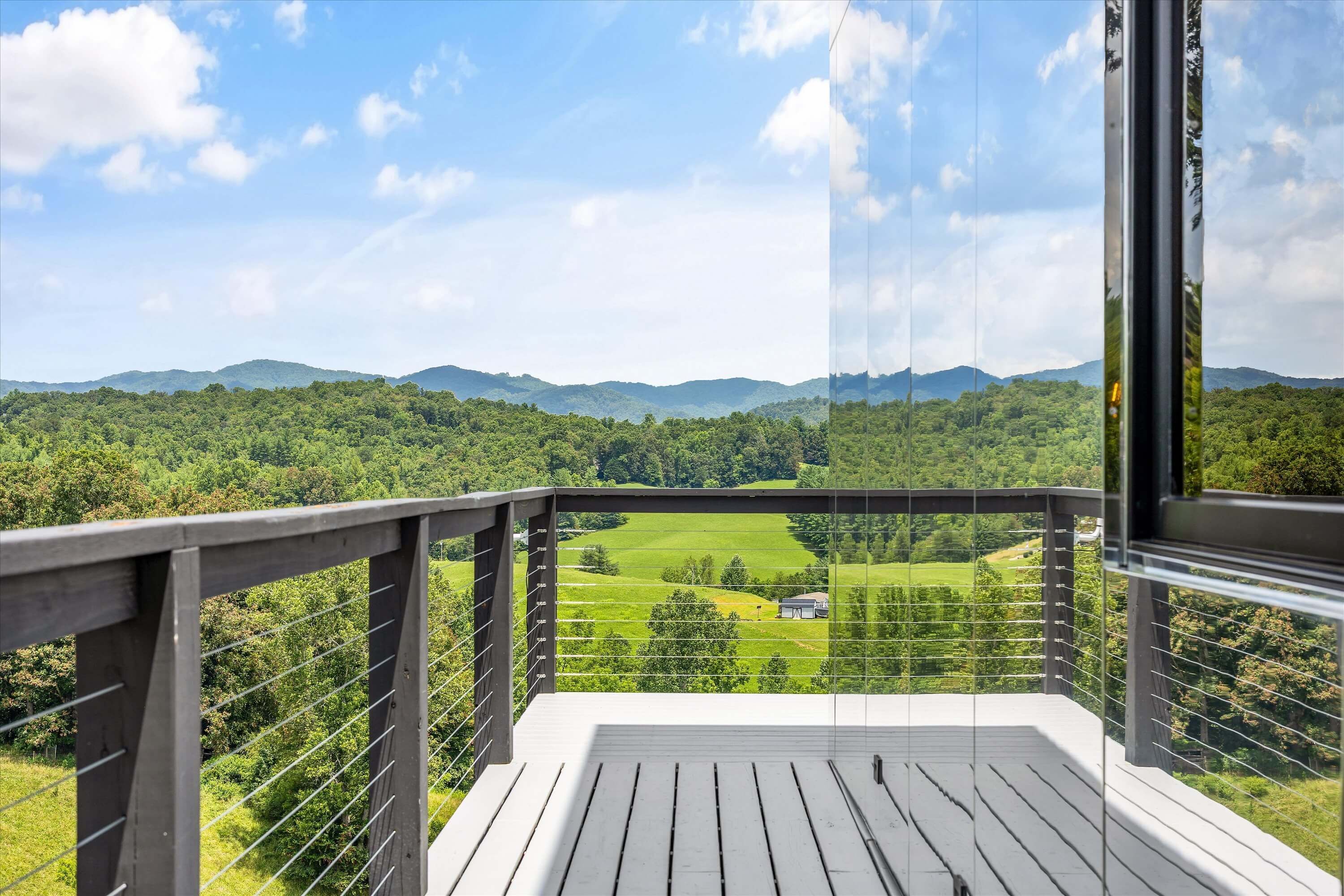 Un balcon offrant une vue sur un paysage verdoyant et des montagnes lointaines.