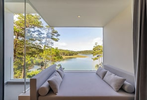 Una habitación moderna con un ventanal grande que da a un lago y árboles.