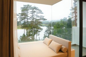 A bedroom with a large window overlooking a lake and trees.