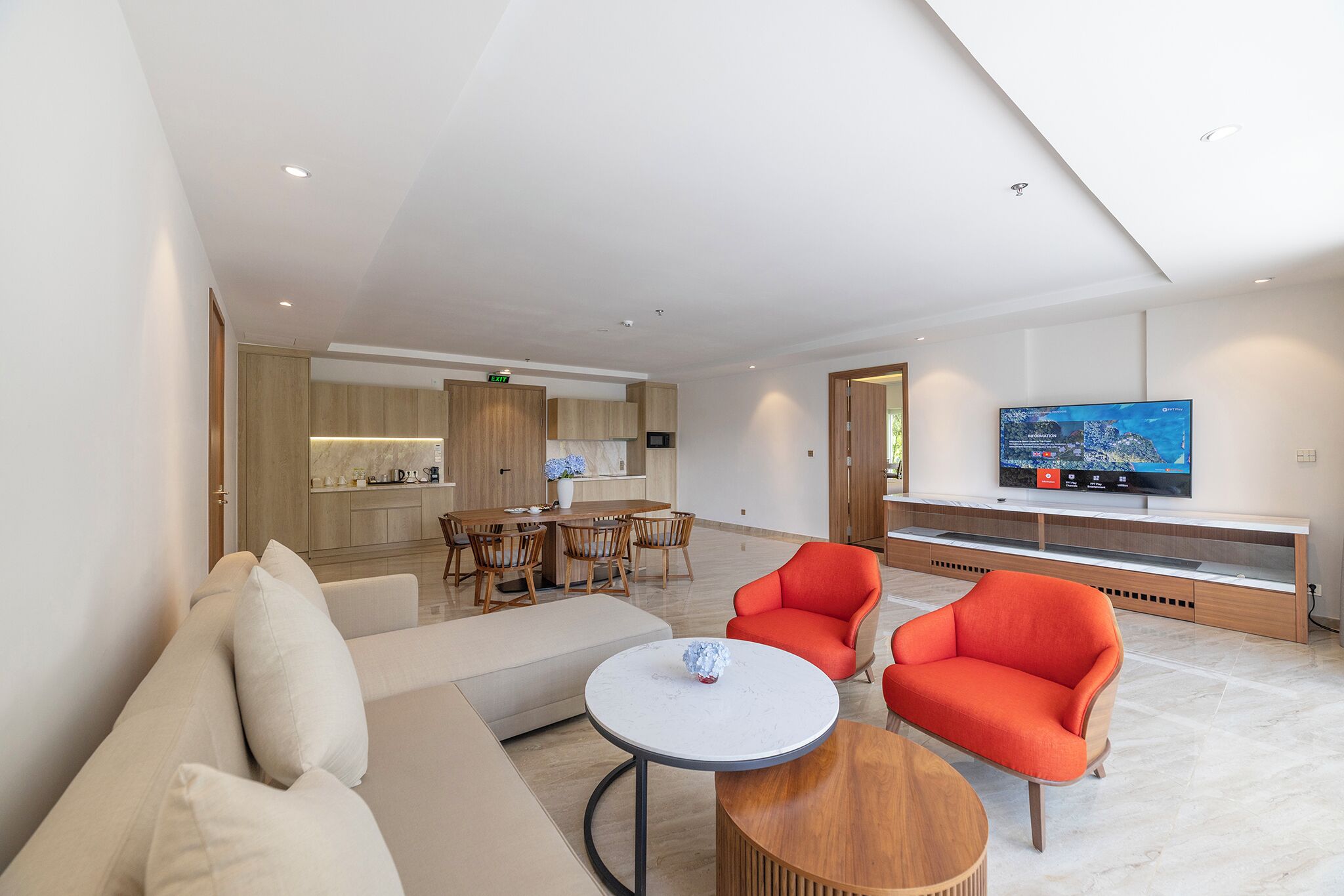 Una habitación de hotel moderna con sala de estar, una mesa de comedor y un televisor.