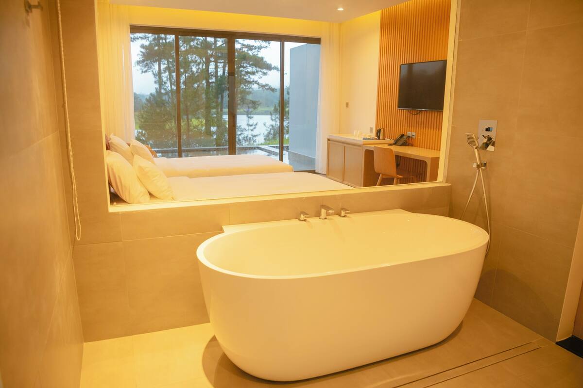 A modern bathroom with a freestanding bathtub, a large mirror, and a desk with a chair.