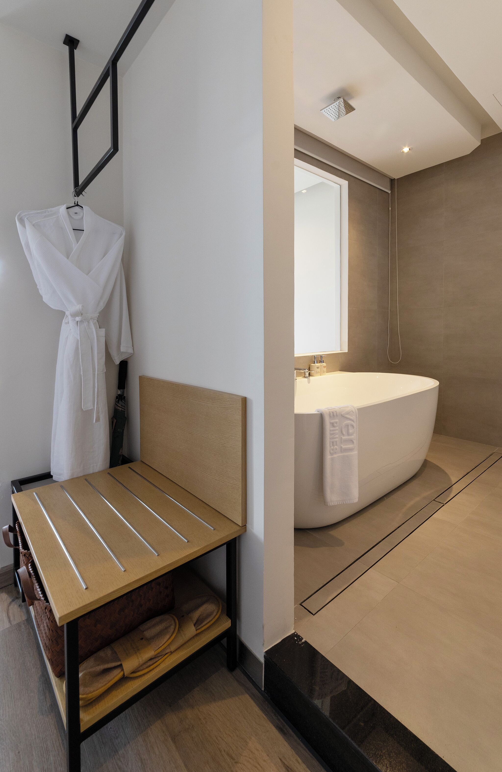 A modern bathroom with a freestanding bathtub, a mirror, and a towel hanging on the wall.