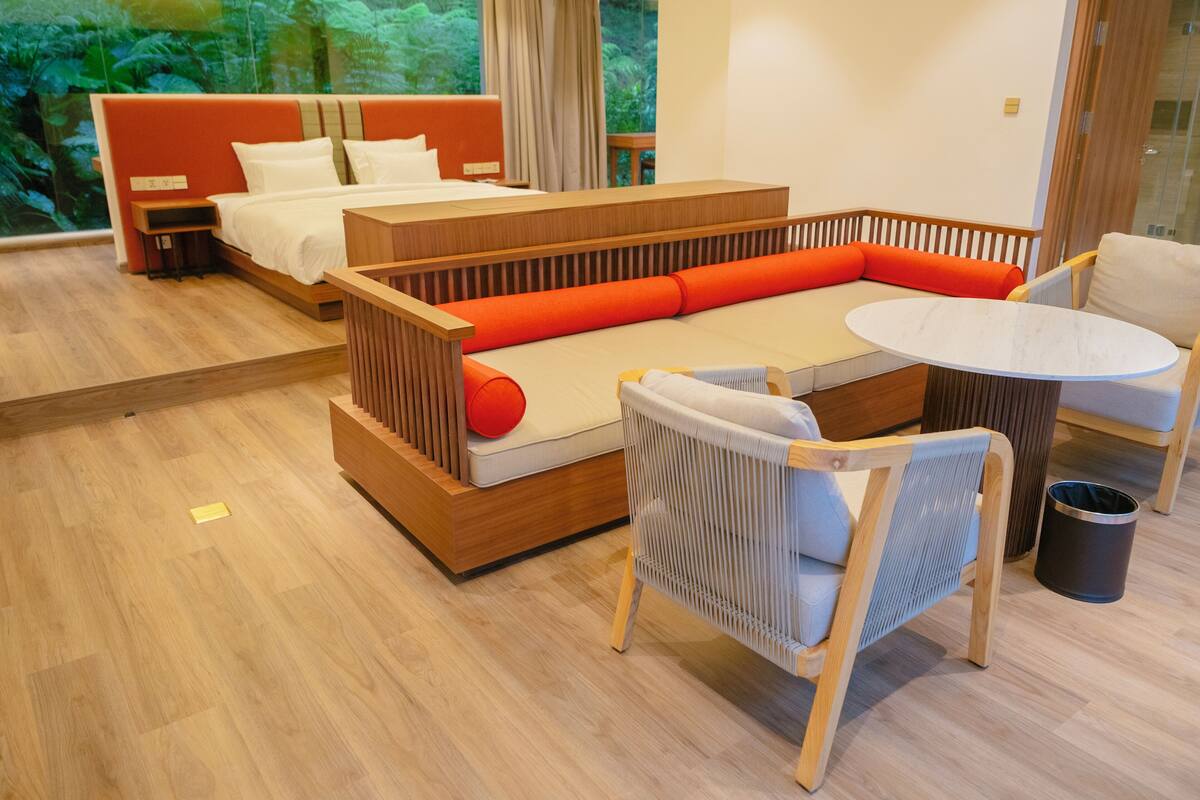 A modern hotel room with a bed, a sofa, a dining table, and a chair.