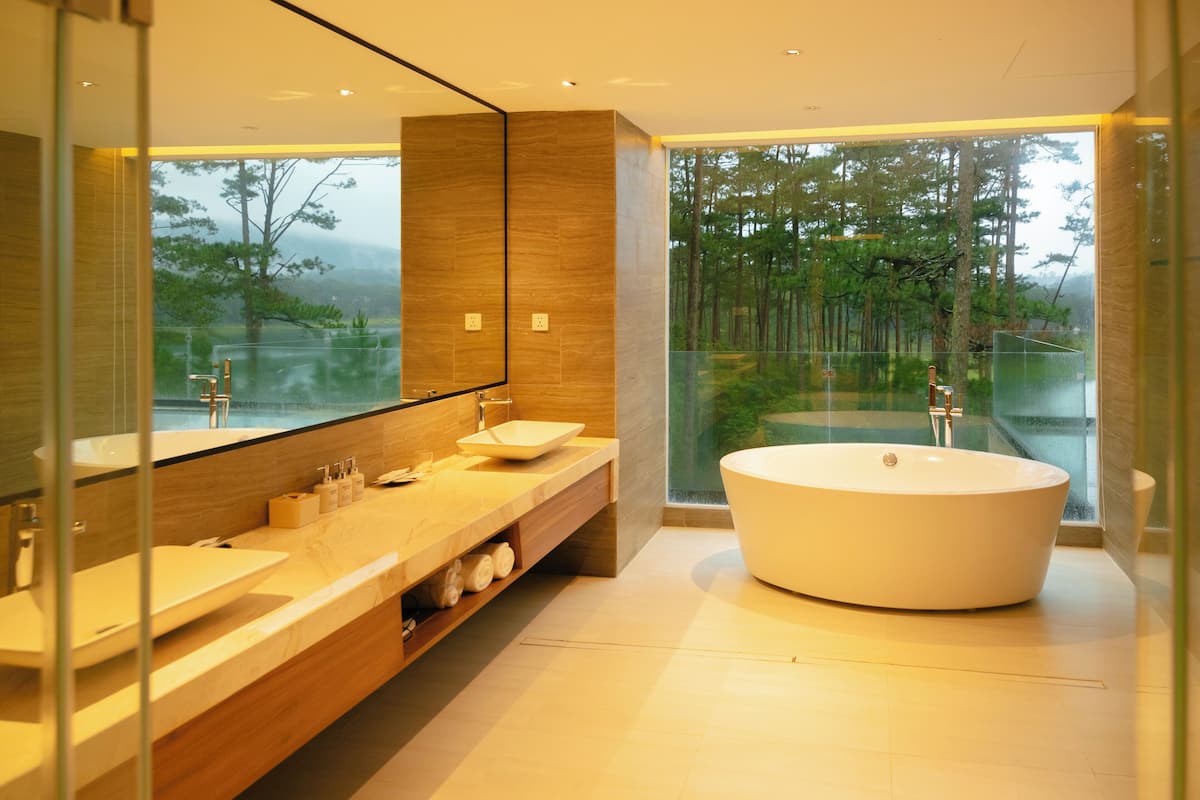 A modern bathroom with a large bathtub, a double sink vanity, and a large mirror.