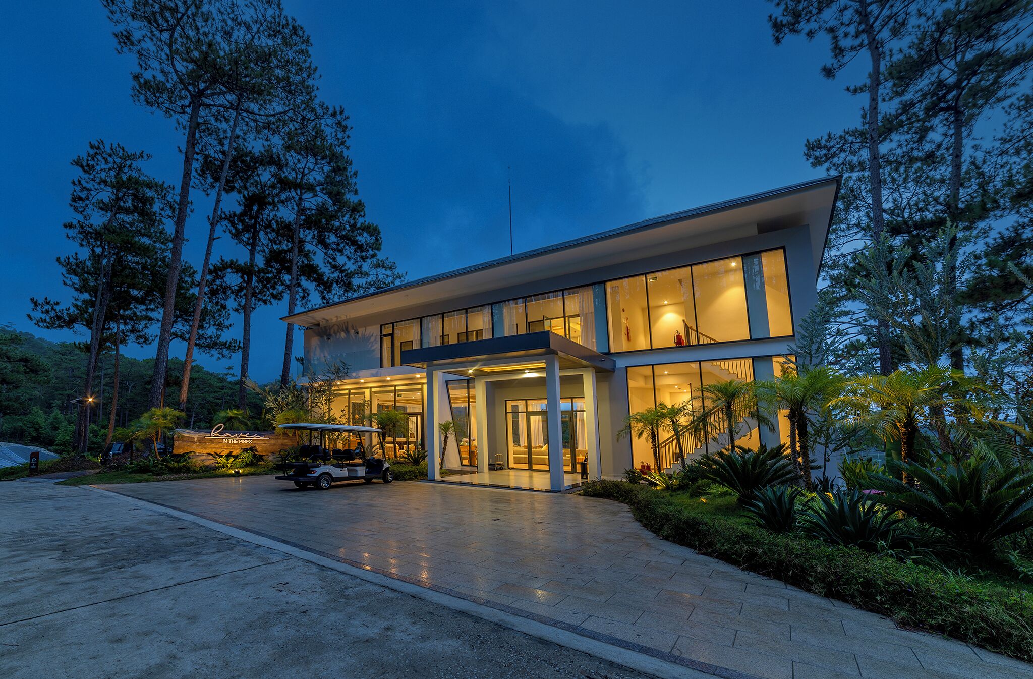 Een modern gebouw met een glazen gevel, een overdekte ingang en een golfkar op de oprit.