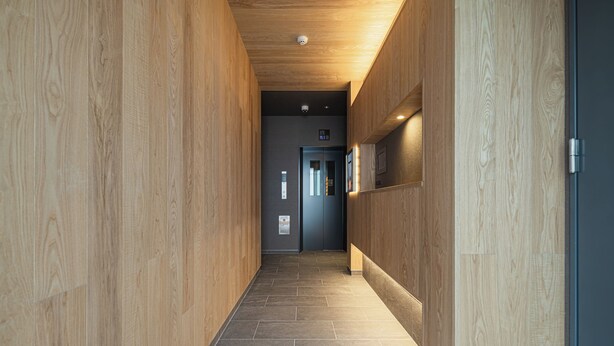 A modern hallway with wooden paneling and a tiled floor. - GRAND BASE MIRAI (Nagasaki)