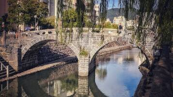Een stenen brug over een kalme rivier, met een helder uitzicht op gebouwen in de verte.