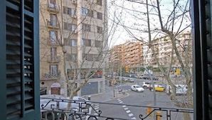 A view from a balcony overlooking a busy intersection with multiple buildings and vehicles. - Spacious 2BR, quick access to Downtown (Barcelona)