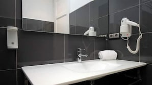 A modern bathroom with a white sink, a mirror, and a hairdryer mounted on the wall. - Spacious 2BR, quick access to Downtown (Barcelona)