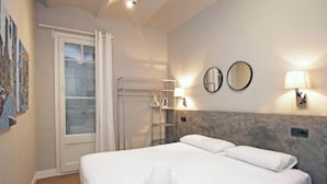Ein Hotelzimmer mit einem Bett, zwei Spiegeln an der Wand, einem Fenster mit Vorhängen und einem Handtuch auf dem Bett.