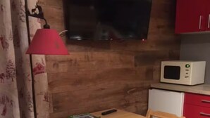 Uma cozinha compacta com micro-ondas, uma mesinha e uma cadeira.