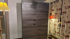 Quarto com guarda-roupa, luminária e cortinas.